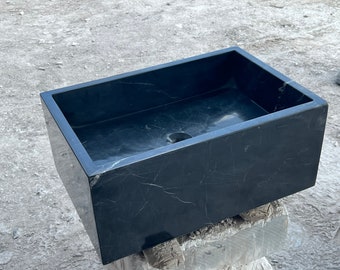 May include: A black marble rectangular sink with a drain hole. The sink is sitting on a wooden surface.
