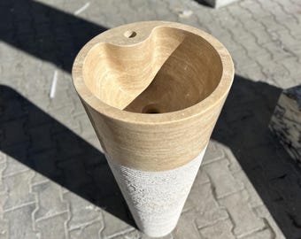 Pode incluir: Uma pia de pedestal bege e branca com uma tigela redonda e uma base texturizada.