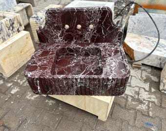 Puede incluir: Un lavabo de mármol rojo y blanco con un salpicadero decorativo. El lavabo está montado sobre una base de madera.