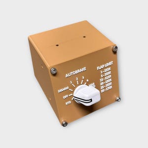 May include: A tan-colored AUTOBRAKE control panel with white lettering and a white and black knob. The panel has text that reads "AUTOBRAKE", "DISARM", "OFF", "RTO", and "FLAP LIMIT". The panel is secured with four silver screws.