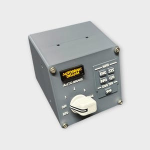 May include: A gray aircraft control panel with the text "AUTOBRAKE DISARM" and "AUTO BRAKE". It features a rotary dial and several buttons labeled "MFD", "ENG SYS", "INFO C/R", and "ENG TFR".