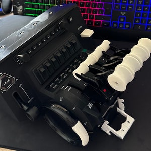 May include: A black flight simulator control panel with white knobs and switches. The panel has a gear lever, flaps lever, and a throttle quadrant. The panel is on a black surface.