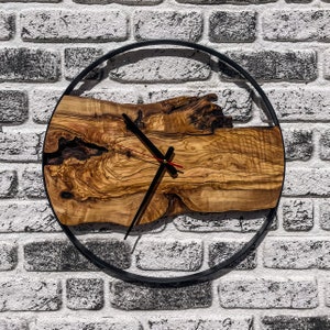 Puede incluir: Un reloj de madera con agujas negras y un marco de metal negro. La esfera del reloj está hecha de una rebanada de madera natural con un patrón de veta único.