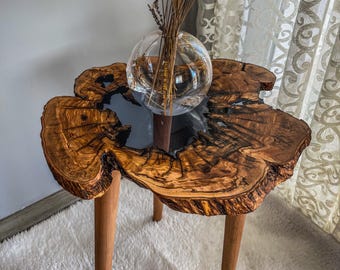 Handgemaakte bijzettafel van olijfhout met epoxyhars, natuurlijke rand en antracietblauwe afwerking.