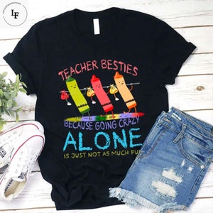 May include: Black t-shirt featuring a graphic of four crayons holding hands and the text "Teacher Besties Because Going Crazy Alone Is Just Not As Much Fun".