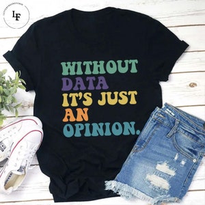 Peut inclure: T-shirt noir avec un graphisme rétro coloré qui dit "Without data it's just an opinion."