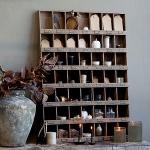 Könnte beinhalten: Ein Holzorganizer mit zahlreichen kleinen Fächern, gefüllt mit verschiedenen dekorativen Gegenständen. Zu den Artikeln gehören kleine Kürbisse, Garnrollen, Etiketten und Kerzen. Der Organizer ist braun und die Artikel sind in neutralen Tönen gehalten.