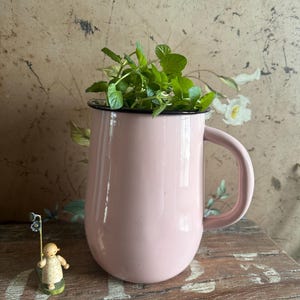 Könnte beinhalten: Ein Set aus drei Keramikbechern mit gesprenkelter, matter Oberfläche. Die Becher sind in Creme-, Hellgrau- und Dunkelgrautönen gehalten. Jeder Becher hat ein schlichtes, minimalistisches Design.