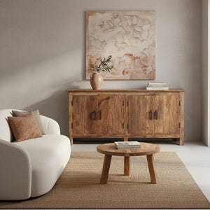 May include: A living room scene featuring a light-colored sofa with decorative pillows, a wooden coffee table, and a large wooden cabinet. A painting hangs above the cabinet. The room is decorated with neutral tones and textures.