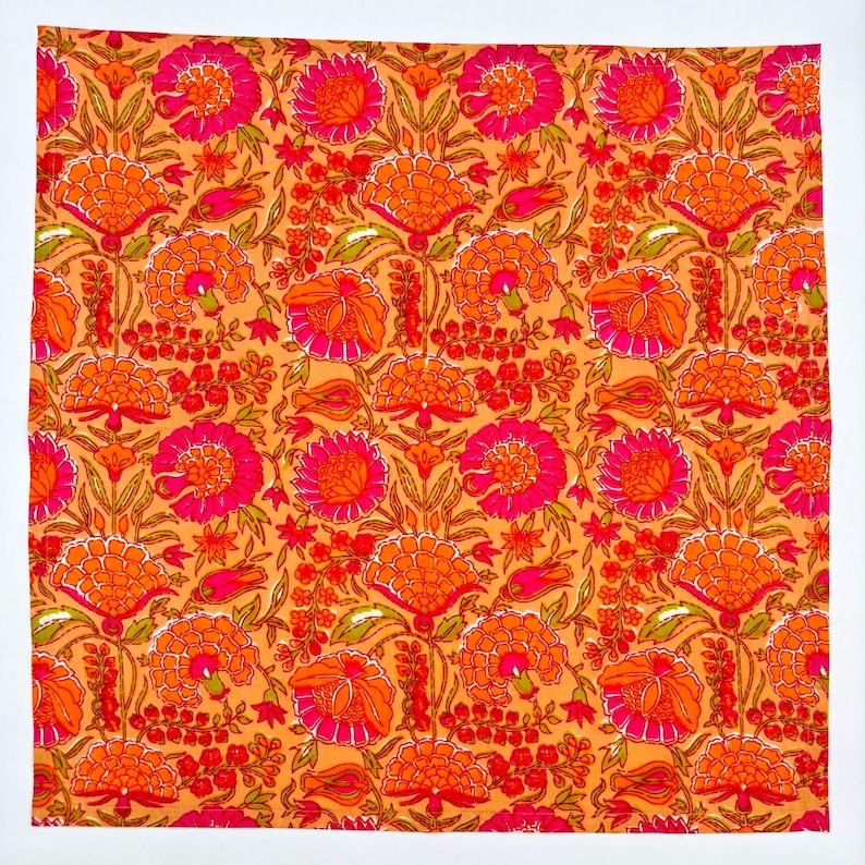 May include: A fabric with a repeating pattern of orange and pink flowers on a peach background.