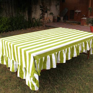 May include: A green and white striped tablecloth with a ruffled edge. The tablecloth is made of cotton and is perfect for a casual outdoor dining setting.
