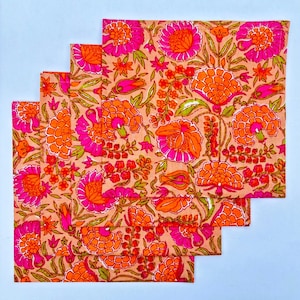 May include: Set of four pink and orange floral cotton napkins. The napkins feature a repeating pattern of pink and orange flowers on a light pink background.