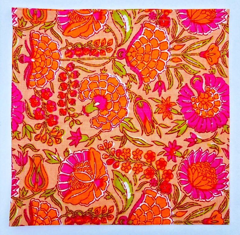 May include: A pink and orange floral print fabric with a white border. The fabric features a repeating pattern of flowers and leaves.