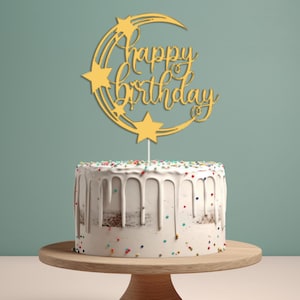 May include: Gold glitter cake topper featuring a crescent moon and stars, with the text "Happy Birthday" in a cursive font.