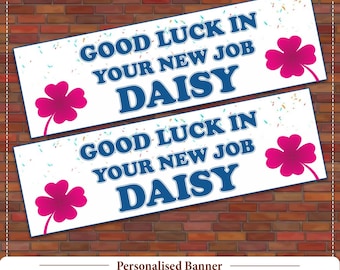 May include: Two white banners with the text "GOOD LUCK IN YOUR NEW JOB DAISY" in blue. Each banner has a pink four-leaf clover and confetti. The banners are on a brick background.