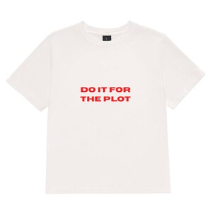 Peut inclure: Un t-shirt à manches courtes et col rond blanc cassé avec le texte "DO IT FOR THE PLOT" imprimé en lettres capitales rouges, grasses et sans empattement au centre de la poitrine. Le vêtement présente une coupe standard avec un col côtelé.