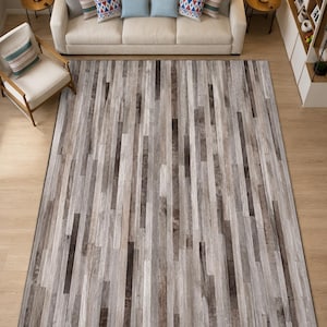 May include: A rectangular area rug featuring a vertical plank pattern in varying shades of gray, charcoal, and white. The design mimics the appearance of weathered wood strips arranged in a linear, repeating sequence across the entire surface.