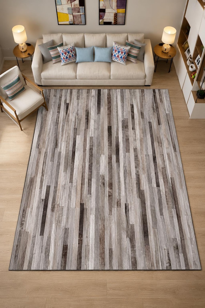 May include: A rectangular area rug featuring a vertical plank pattern in varying shades of gray, charcoal, and white. The design mimics the appearance of weathered wood strips arranged in a linear, repeating sequence across the entire surface.