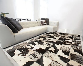 May include: A white sectional sofa with black and white patterned pillows sits on a black and white cowhide rug in a modern living room.