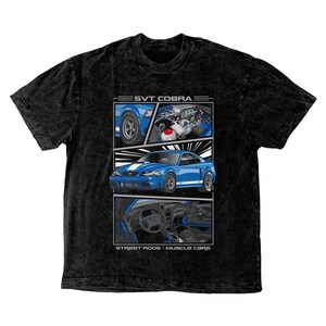May include: Black mineral wash t-shirt featuring a graphic of a blue SVT Cobra car. The graphic includes detailed illustrations of the car's exterior, engine, and interior. Text reads "SVT Cobra" and "Street Rods - Muscle Cars."