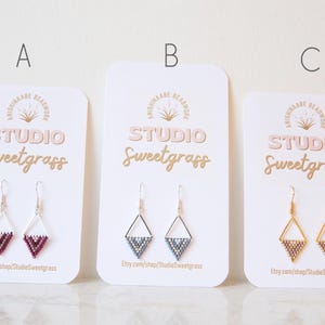 Peut inclure: Trois paires de boucles d'oreilles en perles faites à la main, présentées sur des cartes blanches. Les boucles d'oreilles ont la forme d'un triangle et sont disponibles en trois couleurs : rose, bleu et or.