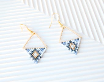 Könnte beinhalten: Ein Paar goldene Dreiecksohrringe mit einem geometrischen Muster aus blauen, weißen und braunen Perlen.