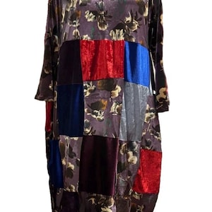 Peut inclure: Une robe à manches longues présentant un motif patchwork composé de tissus à fleurs dans des tons de violet et de marron, alternant avec des carrés de velours unis rouge vif, bleu profond et bordeaux foncé, dotée d'une encolure en V.