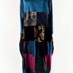 Może przedstawiać: Długa sukienka z welwetu w kolorze morskim z patchworkiem. Patchwork zawiera kwadraty z czarnych, kwiatowych i gładkich tkanin w kolorze morskim, fioletowym i różowym. Sukienka jest prezentowana na manekinie.