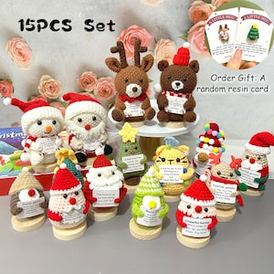 May include: A collection of 15 crocheted Christmas decorations, featuring snowmen, Santas, reindeer, bears, and Christmas trees. Each ornament is on a wooden base and holds a small card. The text "15PCS Set" is at the top.