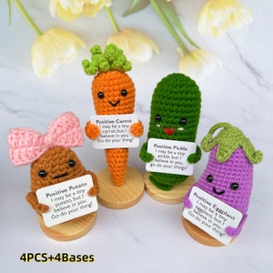 May include: Four crocheted vegetable plushies with wooden bases. Each plush holds a sign with a positive message. The plushies are a carrot, potato, pickle, and aubergine. The signs read: "Positive Carrot I may be a tiny carrot, but I believe in you. Go do your thing!" "Positive Potato I may be a tiny potato, but I believe in you. Go do your thing!" "Positive Pickle I may be a tiny pickle, but I believe in you, go do your things!" "Positive Eggplant I may be a tiny eggplant, but I believe in you. Go do your thing!"