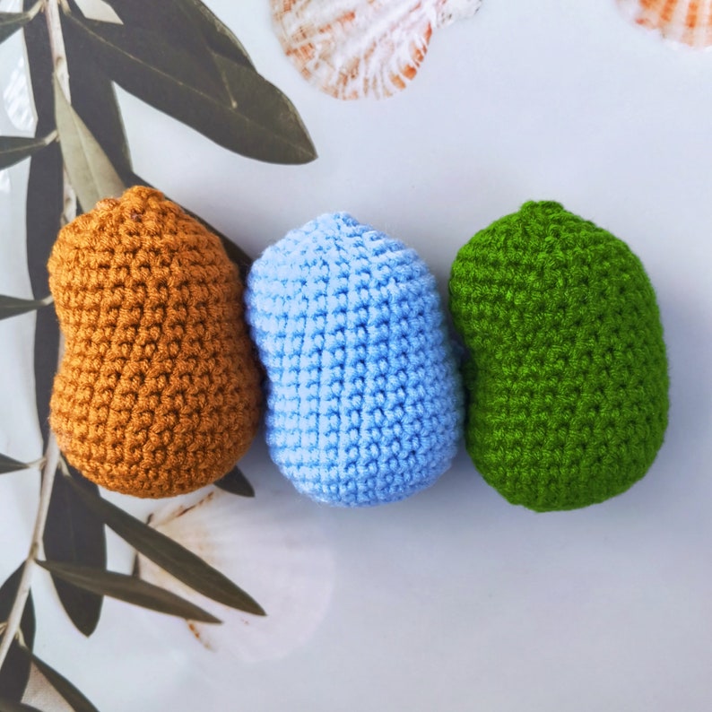 May include: Three crocheted egg-shaped ornaments in brown, blue and green.