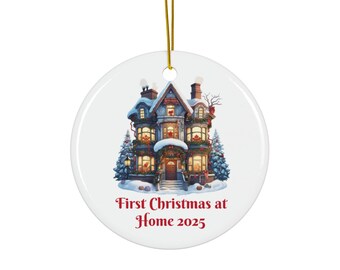 May include: A round white Christmas ornament with a detailed illustration of a house covered in snow and decorated for the holidays. The text "First Christmas at Home 2025" is printed in red. A gold string is attached for hanging.