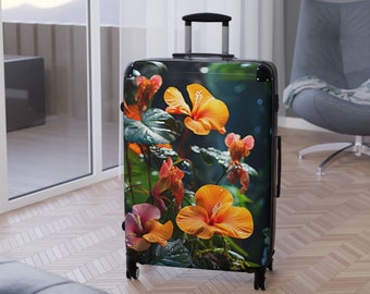 Könnte beinhalten: Ein schwarzer Rollkoffer mit einem lebendigen Blumendesign, das orangefarbene und rosa Hibiskusblüten und üppiges grünes Laub zeigt. Der Koffer hat einen ausziehbaren Griff und vier Räder. Das Thema ist Reisen und Natur.