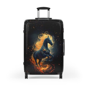 Puede incluir: Maleta rodante negra con un majestuoso caballo negro con melena dorada y detalles de fuego. El caballo se encuentra sobre un fondo oscuro y estrellado. La maleta tiene un asa telescópica y cuatro ruedas.