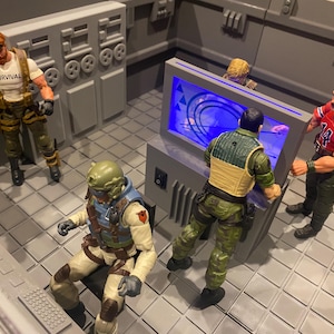 Puede incluir: Escena interior con figuras de acción. Una figura lleva una camiseta blanca con "SURVIVAL" impreso. Otra figura está sentada frente a una computadora. Otras figuras se reúnen alrededor de una gran pantalla azul.