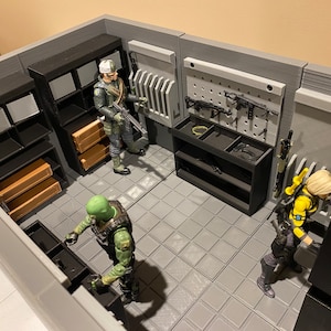 May include: A miniature room set with a gray tiled floor, black shelves, and a pegboard with various weapons. Three action figures are included, one in green camouflage, one in black and yellow, and one in a brown uniform.