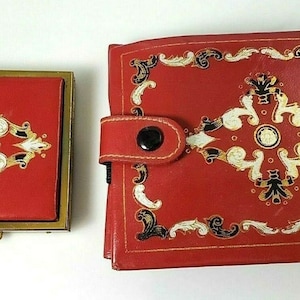 May include: A red leather compact mirror and a matching red leather wallet with gold and white floral designs.