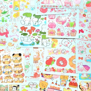 Puede incluir: Una colección de pegatinas coloridas con varios personajes de dibujos animados lindos, incluidos animales, flores y comida. Las pegatinas están dispuestas en un patrón de cuadrícula sobre un fondo blanco. Algunas de las pegatinas tienen texto, como "Donut King" y "Shroom Queens".