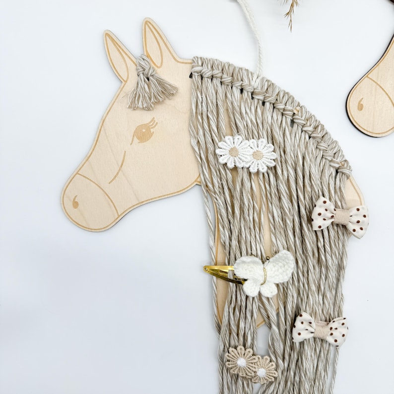 Pu&ograve; includere: Testa di cavallo in legno con una lunga criniera di filato beige. La criniera &egrave; decorata con fermagli per capelli a forma di fiori bianchi e marroni, fermagli per capelli a forma di farfalla bianca e fermagli per capelli a pois marroni.