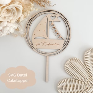 Może przedstawiać: Drewniany topper na tort z motywem żaglówki i tekstem "zur Konfirmation". Żaglówka ma serce na żaglu i girlandę z serduszkami.