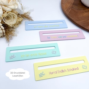 Puede incluir: Cuatro ayudas de lectura de colores pastel con rectángulos recortados y texto. Los colores son azul, rosa, verde y amarillo. Cada ayuda tiene una frase diferente en alemán, con las palabras "ABC" y números. También se ve el texto "3D Druckdatei Lesehilfen".