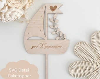 Peut inclure: Décor de gâteau en bois en forme de voilier avec un cœur et des feuilles. Le décor dit "zur Kommunion" en cursive.