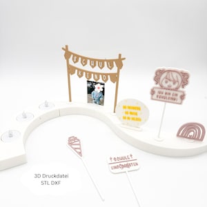 May include: A white, curved display piece with several decorative elements. It features a banner that reads "SCHUL KIND" and a sign that says "ICH BIN EIN SCHULKIND!". Other elements include a rainbow, a cone, and a sign that says "SCHULE KINDERGARTEN".