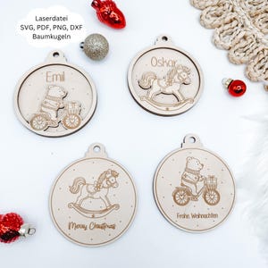 Könnte beinhalten: Weihnachtsschmuck aus Holz mit eingravierten Designs. Einer zeigt einen Bären auf einem Fahrrad, ein anderer ein Schaukelpferd, und zwei weitere haben Text. Die Ornamente sind rund mit einem Loch oben zum Aufhängen.