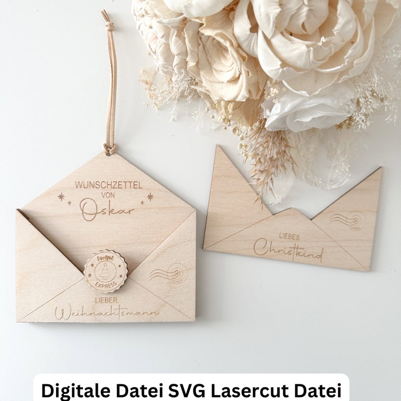 May include: A wooden envelope with a cutout for a wish list. The envelope is decorated with stars and the text "Wunschzettel von Oskar". A small wooden circle with a Christmas tree design and the text "Lieber Weihnachtsmann" is attached to the envelope. A second wooden envelope with the text "Liebes Christkind" is also shown.