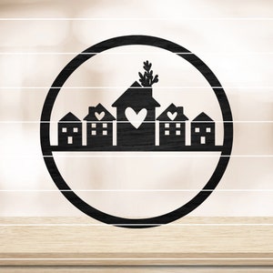 Könnte beinhalten: Schwarze runde Wanddekoration aus Metall mit einer Silhouette einer Reihe von Häusern mit Herzen und einer Pflanze oben.