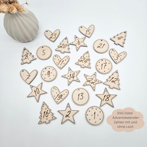 Puede incluir: Un conjunto de 24 adornos navideños de madera en varias formas, incluyendo estrellas, corazones y árboles de Navidad. Cada adorno está cortado con láser y presenta un número del 1 al 24. Los adornos son perfectos para crear un calendario de Adviento único.