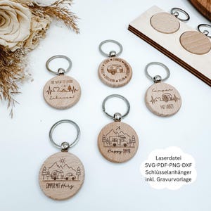 May include: Wooden keychains with silver key rings. The keychains feature engraved designs of campers, mountains, and text. Some keychains have the text "Happy Camper" and "Camper mit Herz". The image also includes text that says "Laserdatei SVG-PDF-PNG-DXF Schlüsselanhänger inkl. Gravurvorlage."