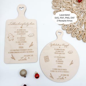 May include: Two wooden cutting boards with heart-shaped handles. One is rectangular and the other is round. Both boards feature engraved recipes for German Christmas cookies, with illustrations of ingredients and the word "Liebe".