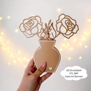 Könnte beinhalten: Eine beige Vase mit weißem Rand und einem kleinen weißen Herzdetail, die zwei lasergeschnittene Rosenblüten und Blätter enthält. Die Blumen und Blätter sind hellbraun. Der Text "3D Druckdatei STL 3MF Vase mit Blumen" ist enthalten.